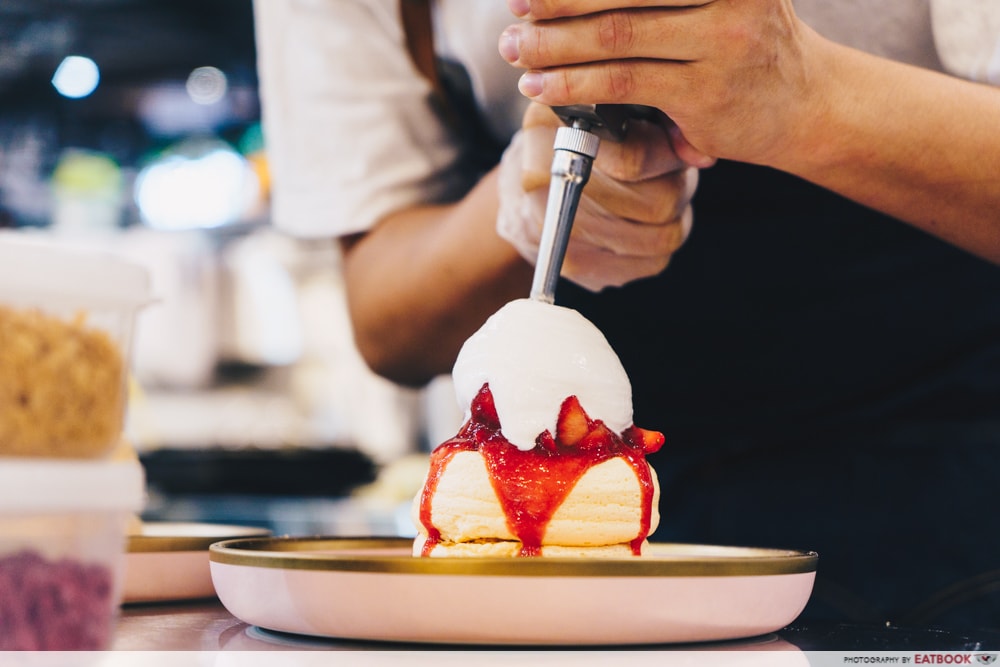 A man puts cream on pancakes