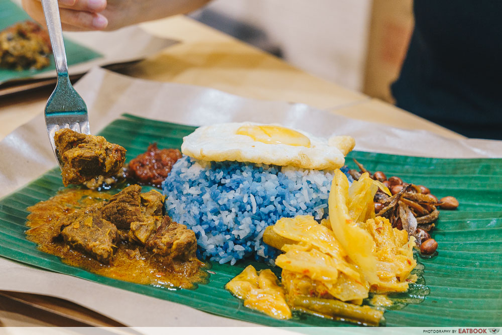 Nasi lemak with blue rice and a sunny side up egg on top