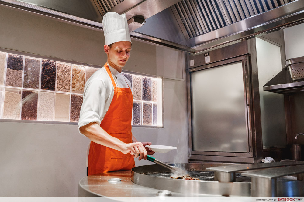 A chef places beef on a grill