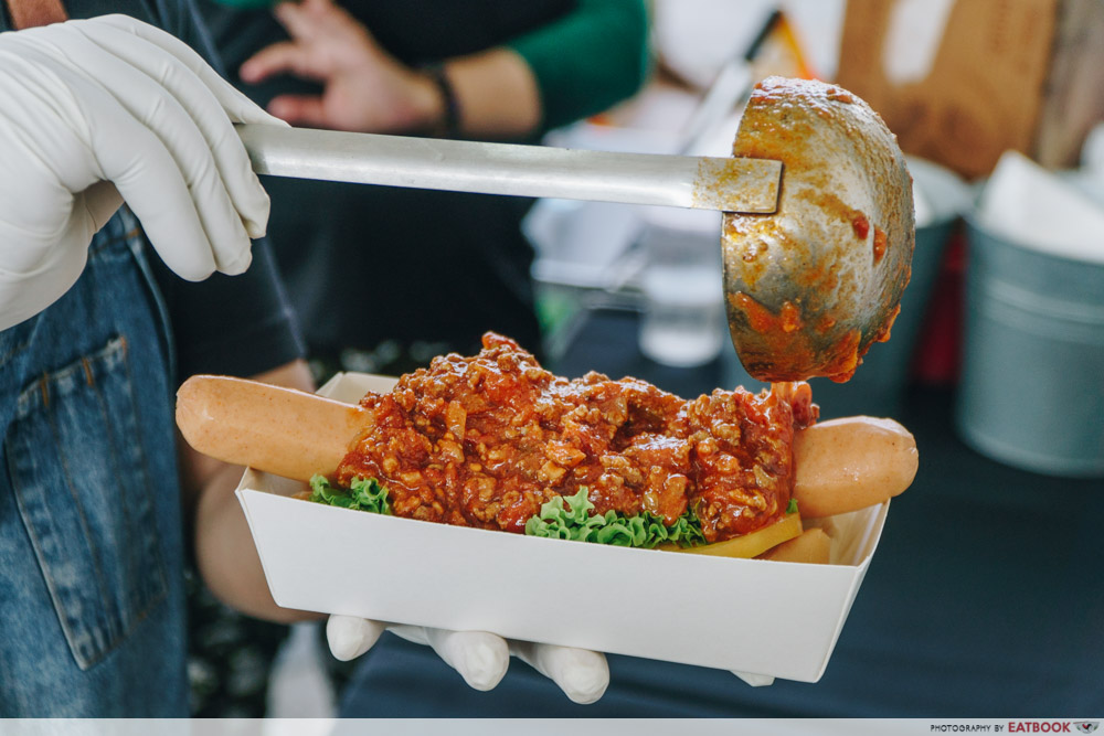 Pouring chilli on hot dog 