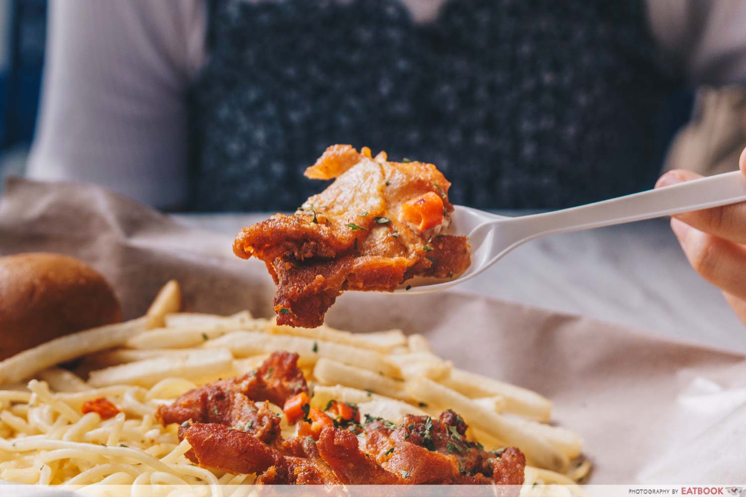 Plastic spoon holding up chicken cutlet meat